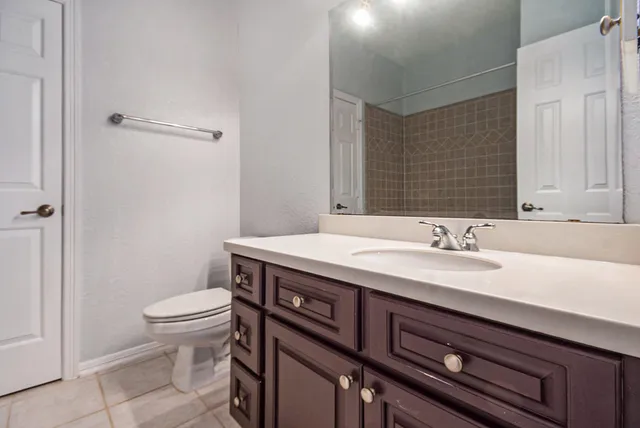 a bathroom with a granite countertop sink a toilet and a mirror