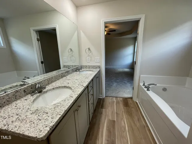 a bathroom with a granite countertop sink a toilet a large mirror and shower