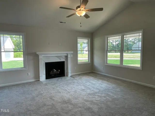 a view of an empty room with window and fireplace