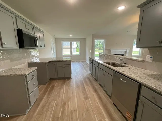 a large kitchen with granite countertop a sink a counter space stainless steel appliances and cabinets