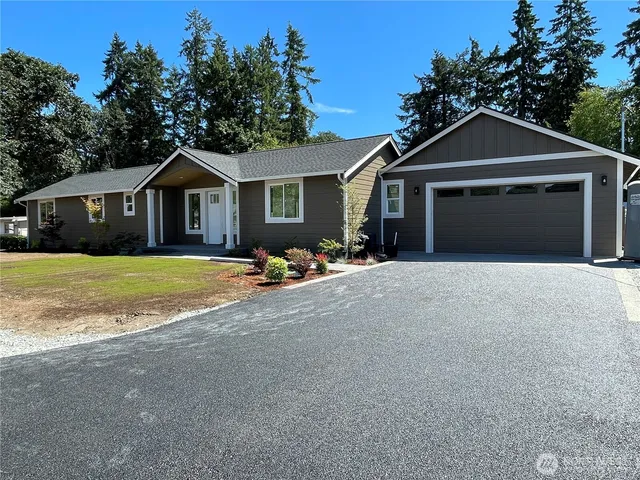 a front view of a house with yard and trees in the background