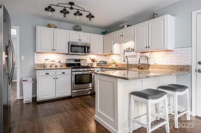 a kitchen with stainless steel appliances granite countertop a white cabinets and stove top oven