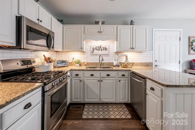 a kitchen with stainless steel appliances granite countertop a sink stove a microwave and cabinets