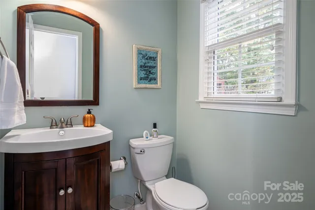 a bathroom with a toilet a sink a mirror and a window