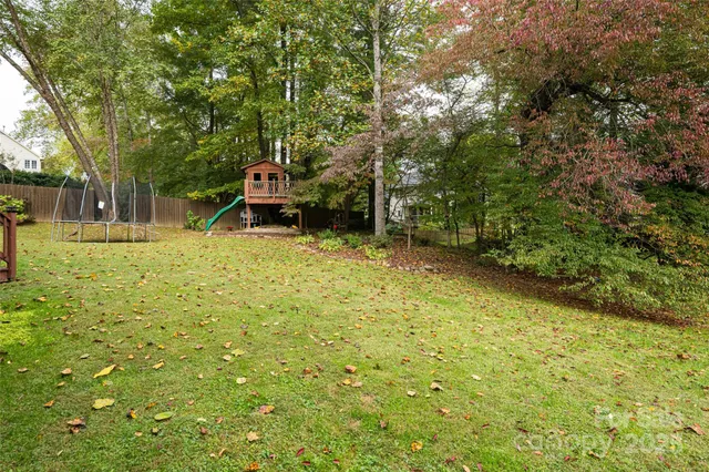 a view of a white house with a big yard and large trees