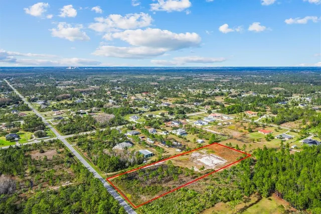 an aerial view of residential houses with outdoor space and trees