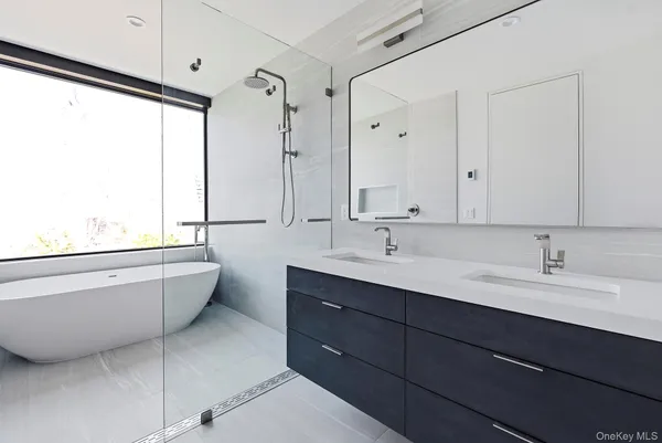 a bathroom with a double vanity sink toilet mirror and bathtub