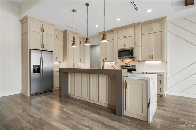 a kitchen with stainless steel appliances granite countertop a refrigerator a oven a sink and white cabinets with wooden floor