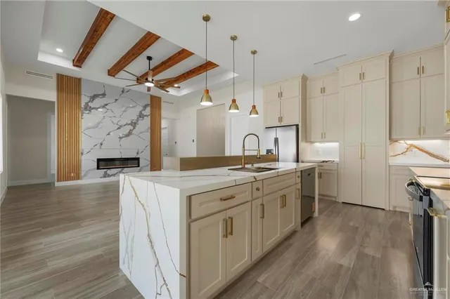 a large kitchen with stainless steel appliances a stove a sink dishwasher and a refrigerator with wooden floor