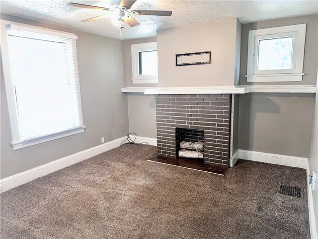 an empty room with windows and fireplace