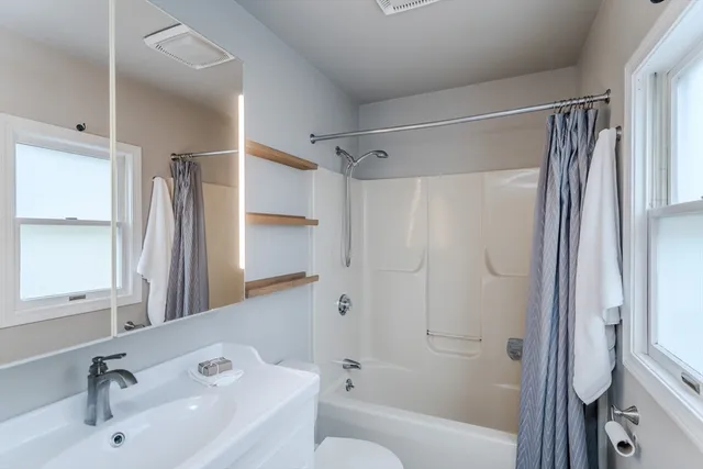 a bathroom with a bathtub shower sink vanity and a toilet