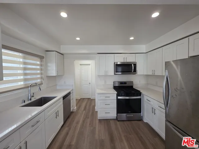 a kitchen with white cabinets and window