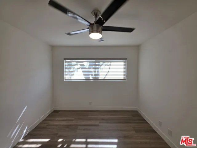 an empty room with wooden floor a ceiling fan and windows