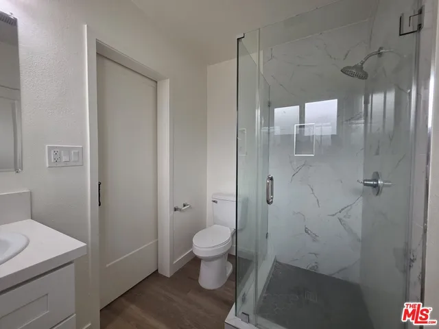 a view of a hallway with wooden floor and a bathroom