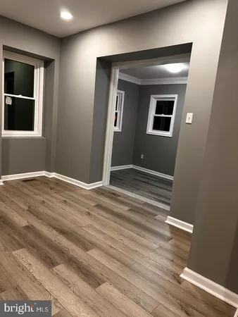 a view of an empty room with wooden floor and windows