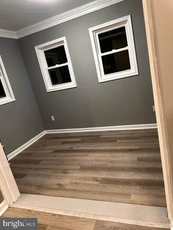 a view of an empty room with wooden floor and windows