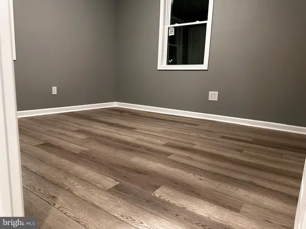 a view of an empty room with wooden floor and closet