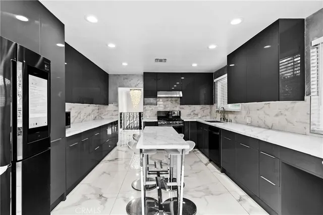 a large kitchen with stainless steel appliances kitchen island granite countertop a stove a sink a refrigerator and a microwave