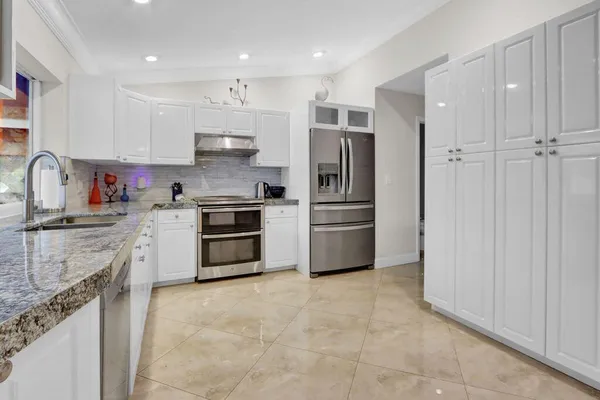 a kitchen with granite countertop a refrigerator oven a sink and cabinets