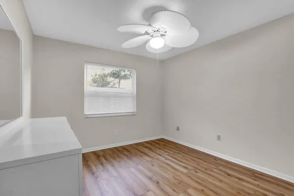 a view of empty room with wooden floor and fan