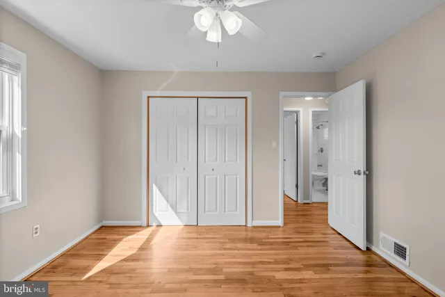a view of a bedroom with wooden floor and a ceiling fan