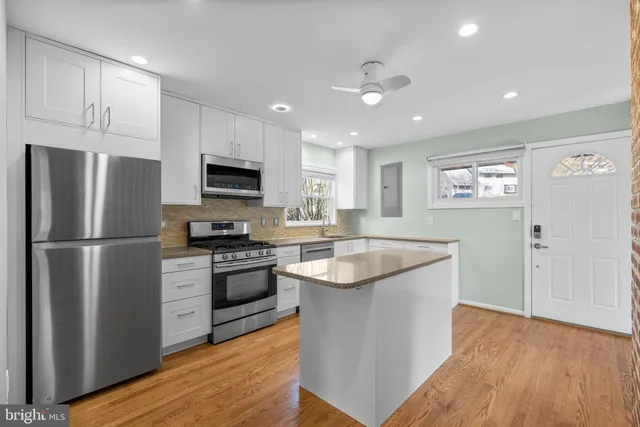 a kitchen with stainless steel appliances granite countertop a refrigerator a stove top oven a sink and dishwasher with wooden floor