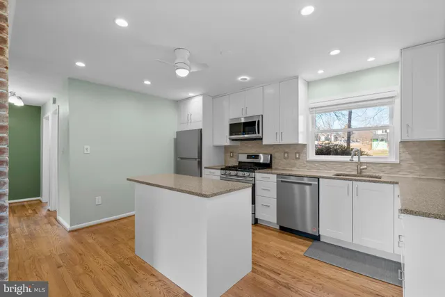 a kitchen with kitchen island granite countertop appliances cabinets a sink and a counter top space