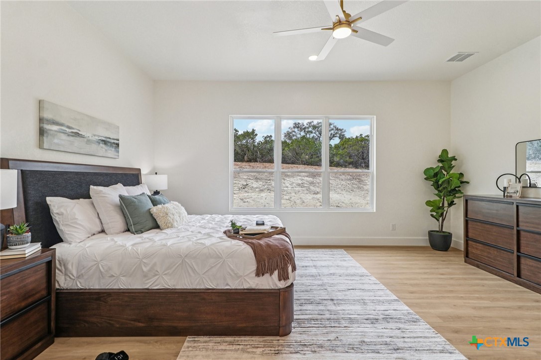 858 Rutherford Fischer, TX 78623 - Photo 15 of 37 a bedroom with a large bed and a potted plant