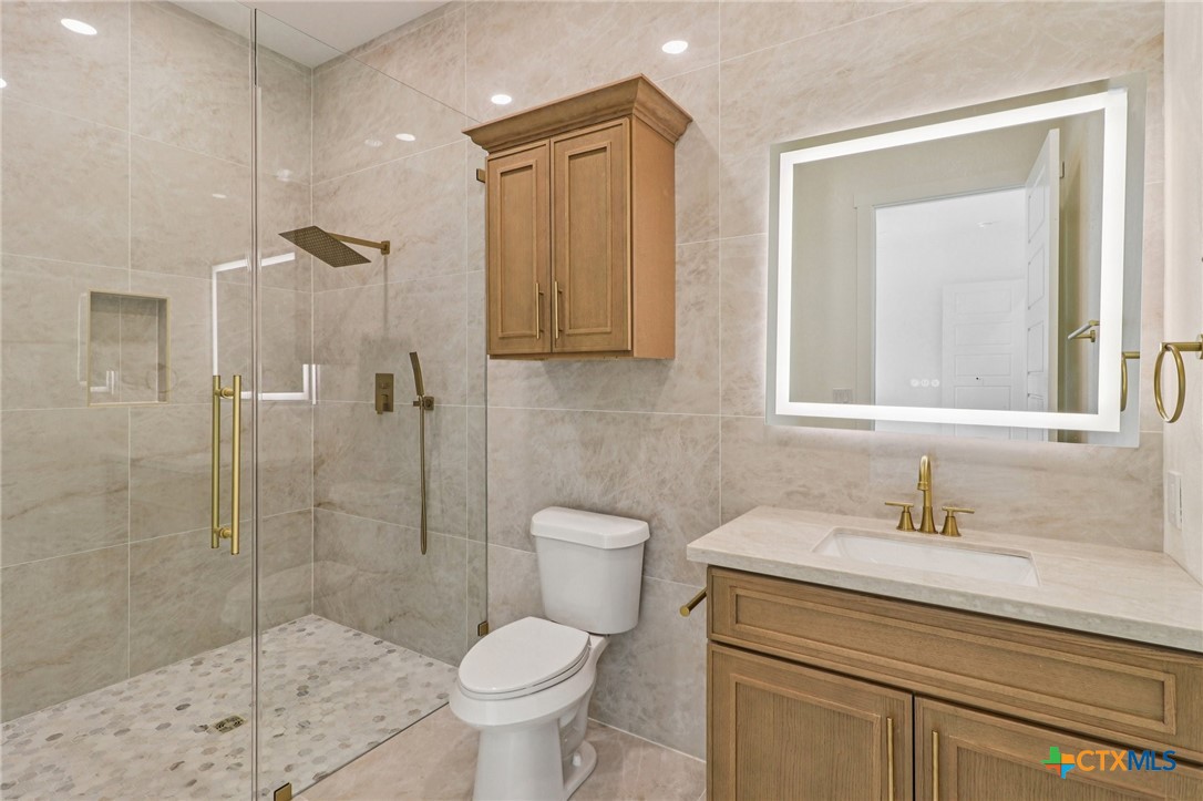 858 Rutherford Fischer, TX 78623 - Photo 26 of 37 a bathroom with a toilet sink vanity and shower