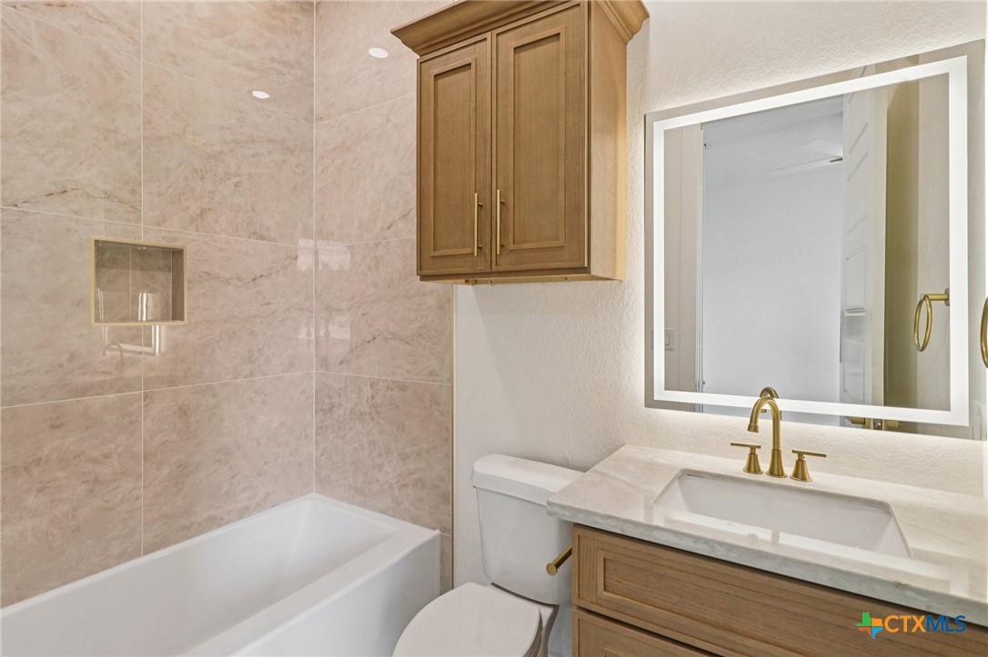 858 Rutherford Fischer, TX 78623 - Photo 28 of 37 a bathroom with a granite countertop sink toilet a mirror and bathtub