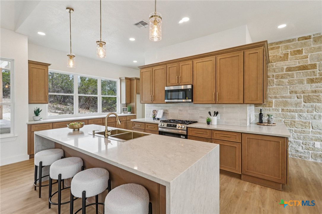 858 Rutherford Fischer, TX 78623 - Photo 4 of 37 a kitchen with kitchen island granite countertop a sink a center island stainless steel appliances and cabinets