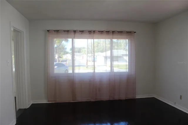 a view of an empty room with wooden floor and a window