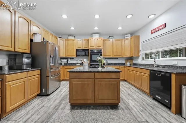 a kitchen with stainless steel appliances granite countertop a refrigerator a stove top oven a sink and dishwasher with wooden floor