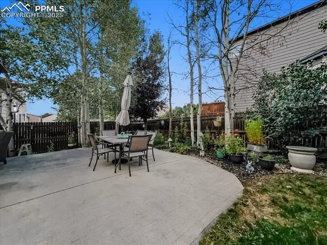 a view of a patio with table and chairs potted plants and large tree