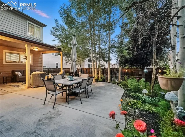 a view of a patio with table and chairs potted plants and large tree