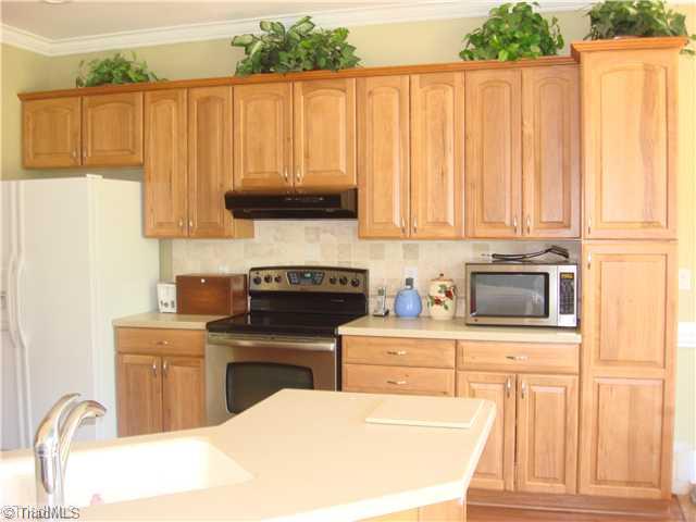 6365 Robinhood Road Pfafftown, NC 27040 - Photo 5 of 16 Kitchen. No need for updating...beautiful custom cabinets, solid surface countertops, tile backsplash and hardwoods are all showcased in this open kitchen.