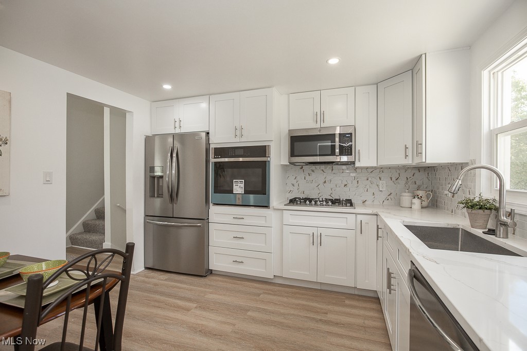 4670 Green Road Cleveland, OH 44128 - Photo 11 of 38 Kitchen featuring stainless steel appliances, sink, light wood-type flooring, and white cabinetry