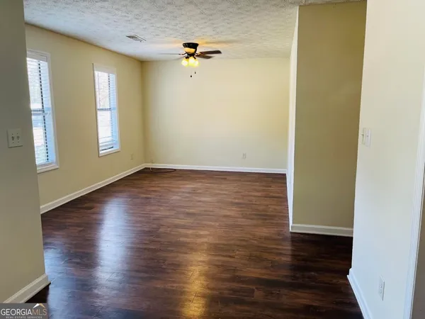 an empty room with wooden floor and windows