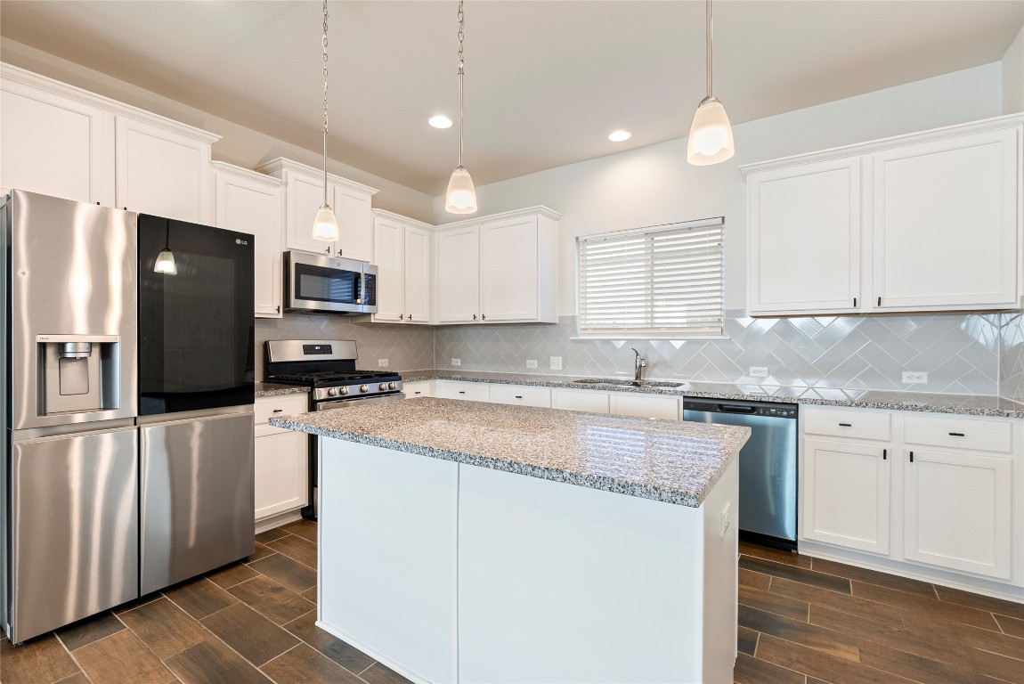 10708 Blacket Drive Austin, TX 78747 - Photo 6 of 20 a kitchen with granite countertop a refrigerator a sink a stove a microwave and island
