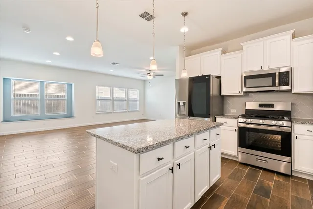 a kitchen with granite countertop a refrigerator a sink a stove a microwave and island