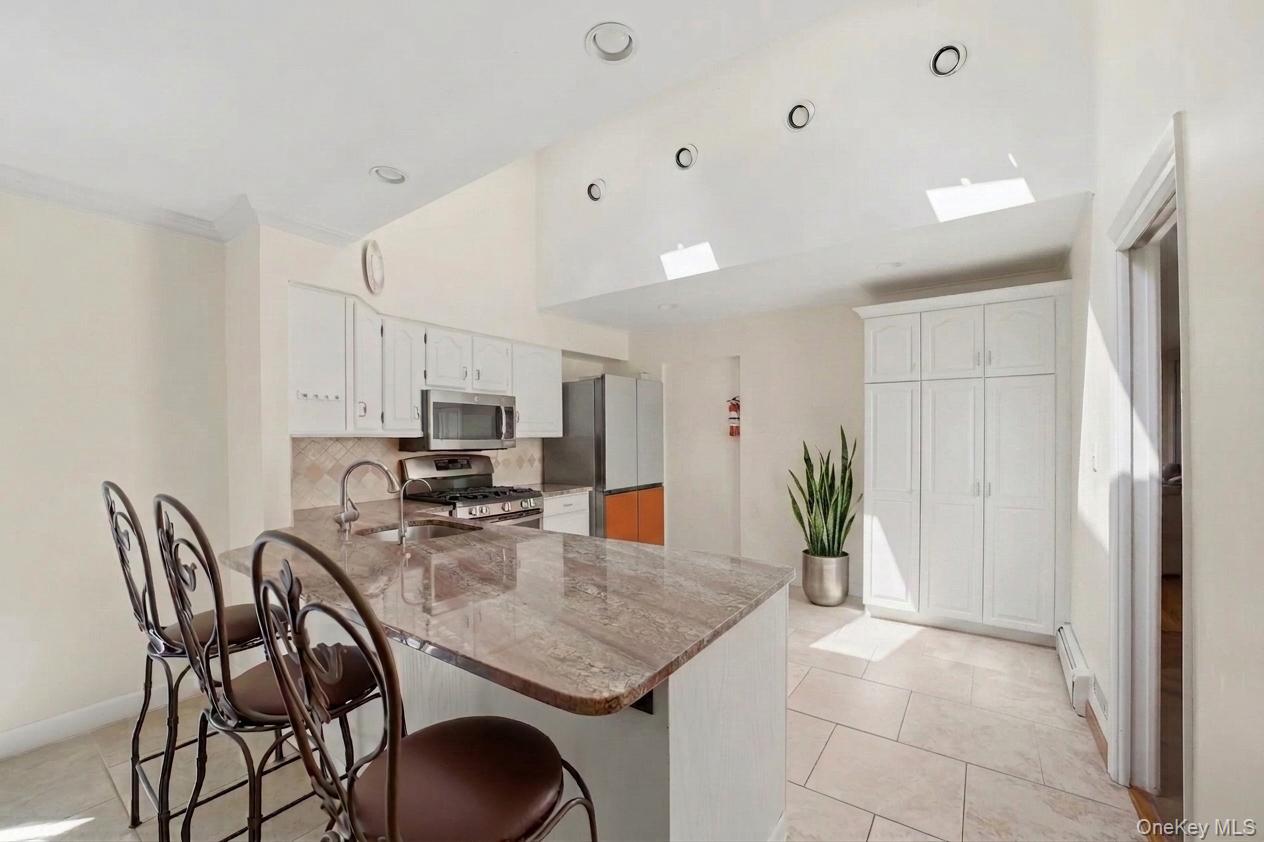 29 Montrose Road Yonkers, NY 10710 - Photo 8 of 39 Kitchen featuring a large island with stone countertop, stainless steel appliances, white cabinetry, sky light, and recessed lighting