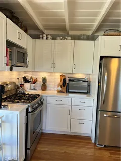 a kitchen with stainless steel appliances granite countertop a stove a refrigerator a dining table and chairs with wooden floor
