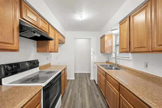 a kitchen with stainless steel appliances granite countertop a sink a stove and a wooden cabinets