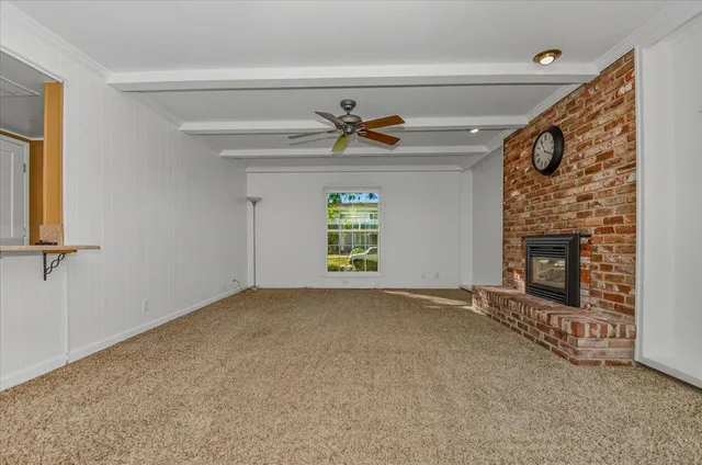 an empty room with chandelier fan and windows