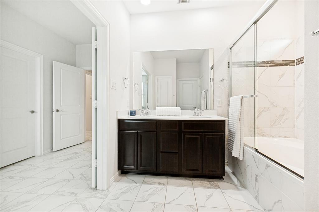 605 Ansley Way Allen, TX 75013 - Photo 20 of 28 Bathroom featuring a double vanity with dark wood cabinetry, a large mirror, and a white countertop