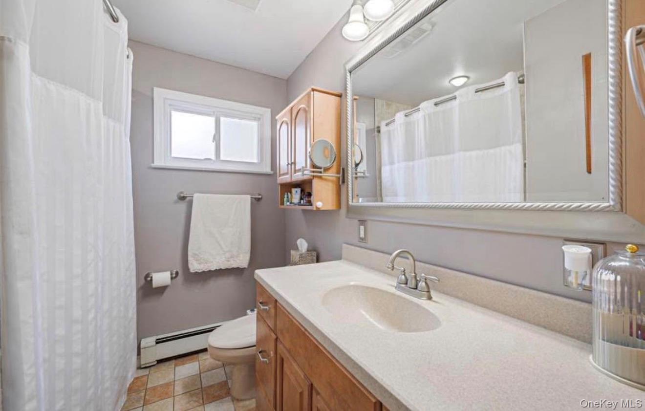 1215 America Avenue West Babylon, NY 11704 - Photo 3 of 13 a bathroom with a sink a toilet and a mirror