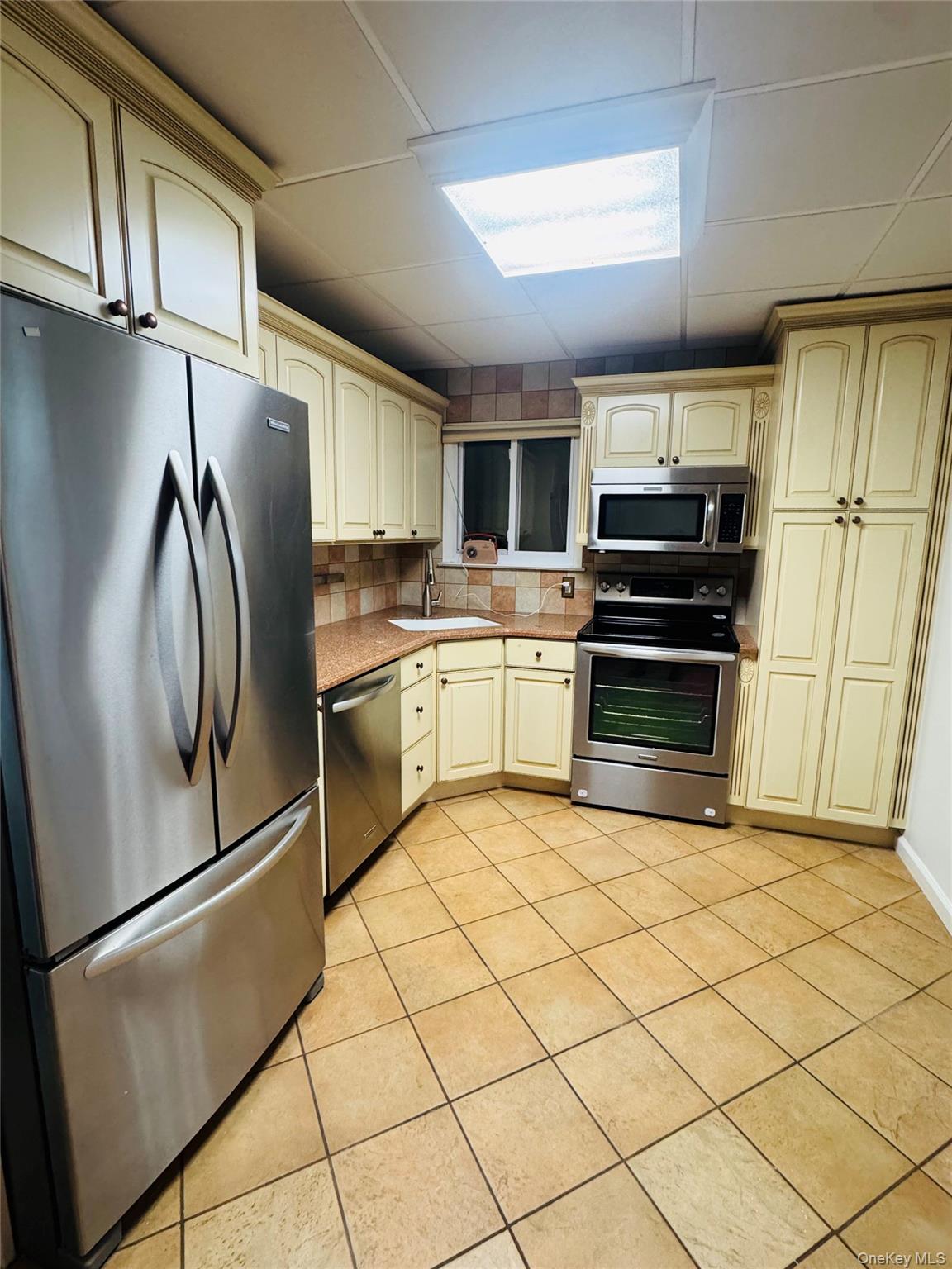 1215 America Avenue West Babylon, NY 11704 - Photo 4 of 13 a kitchen with stainless steel appliances a refrigerator sink and cabinets