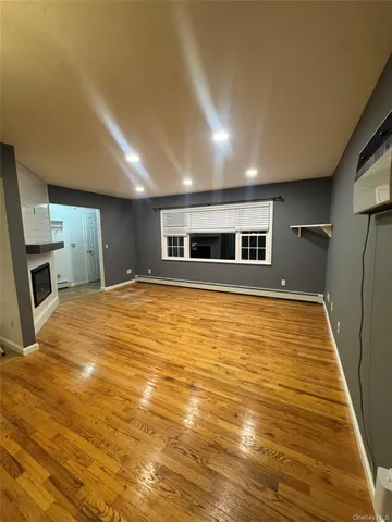 a view of empty room with wooden floor and fireplace