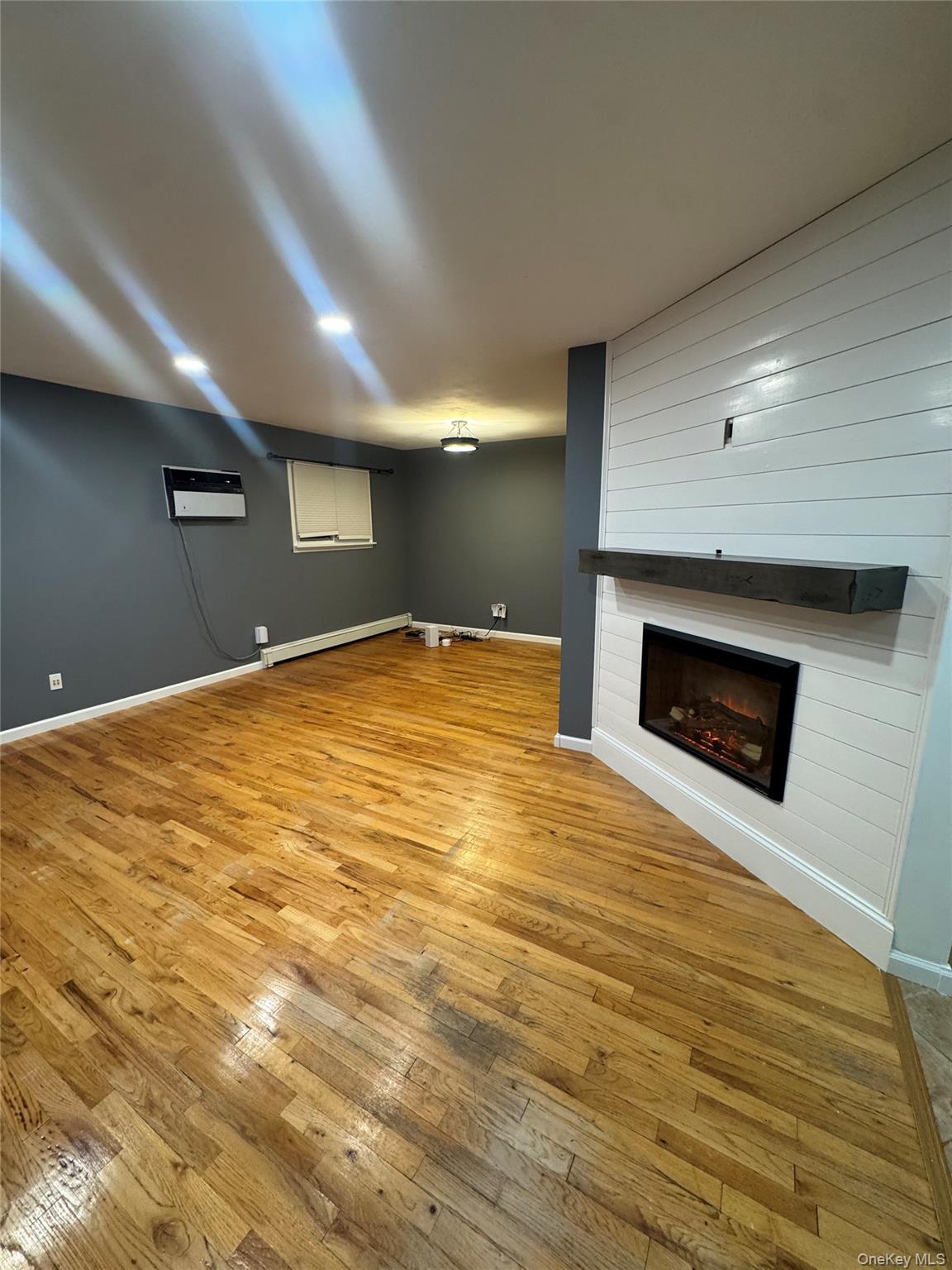 1215 America Avenue West Babylon, NY 11704 - Photo 6 of 13 a view of empty room with wooden floor and fireplace