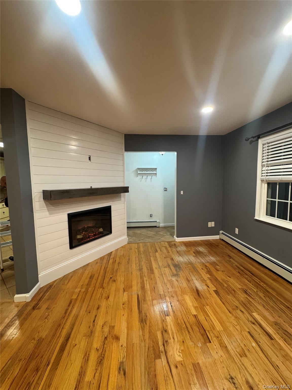 1215 America Avenue West Babylon, NY 11704 - Photo 7 of 13 a view of empty room with wooden floor and fireplace